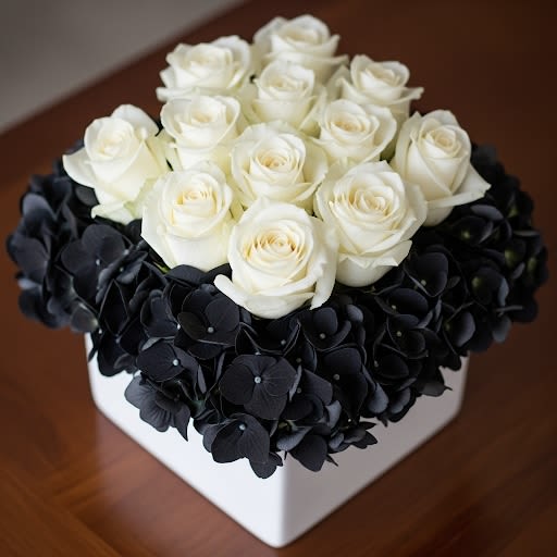 White roses in a square box surrounded by dark hydrangeas