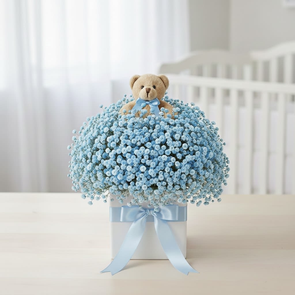 Blue baby's breath arrangement with a teddy bear topper in a white box