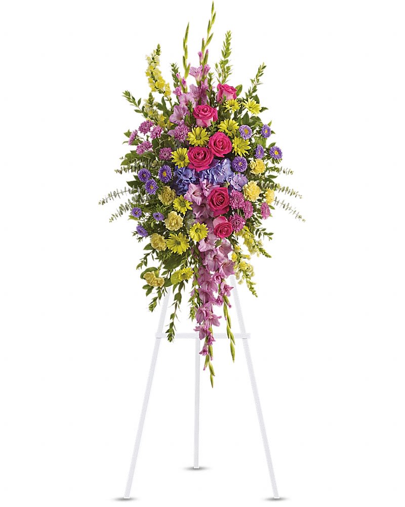 Tall standing floral spray with pink, purple, and yellow flowers on a white easel