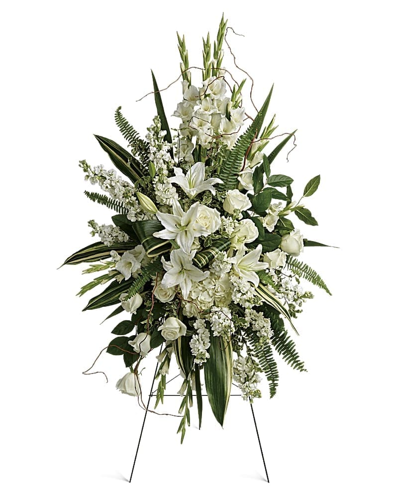 White floral standing spray on an easel with lilies and roses