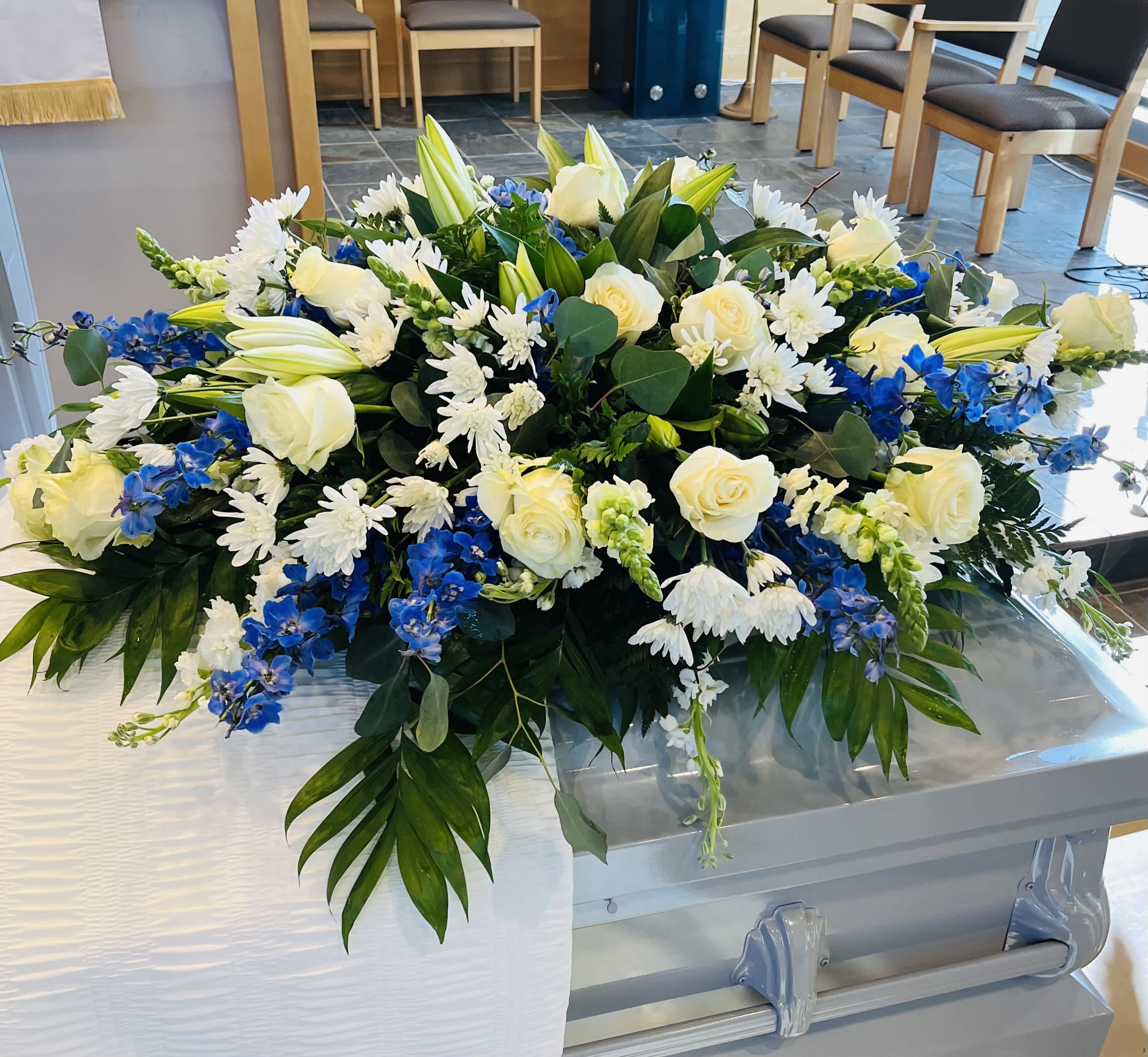 Large white and blue floral casket spray with roses and lilies