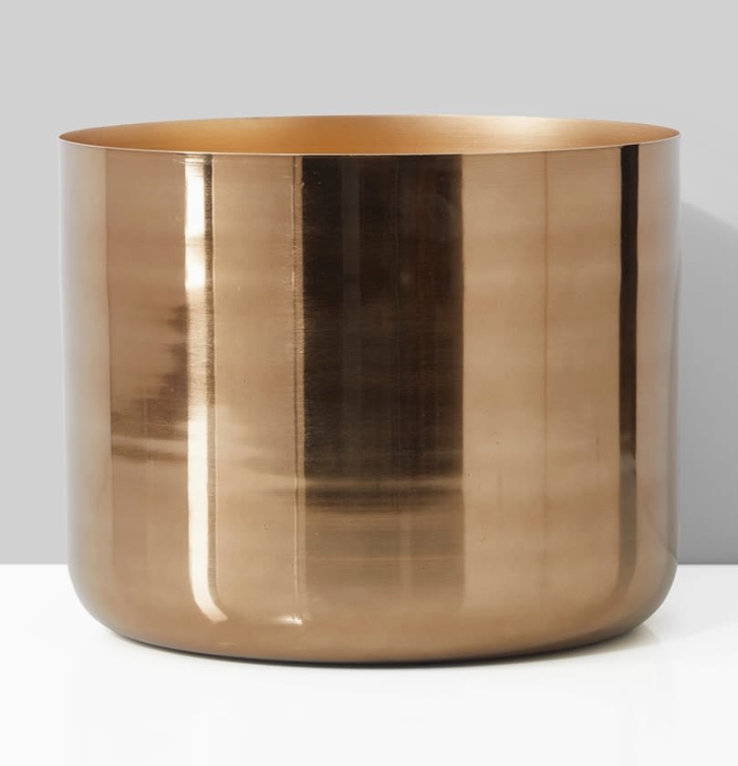 Gold metallic cylindrical vase on a plain background