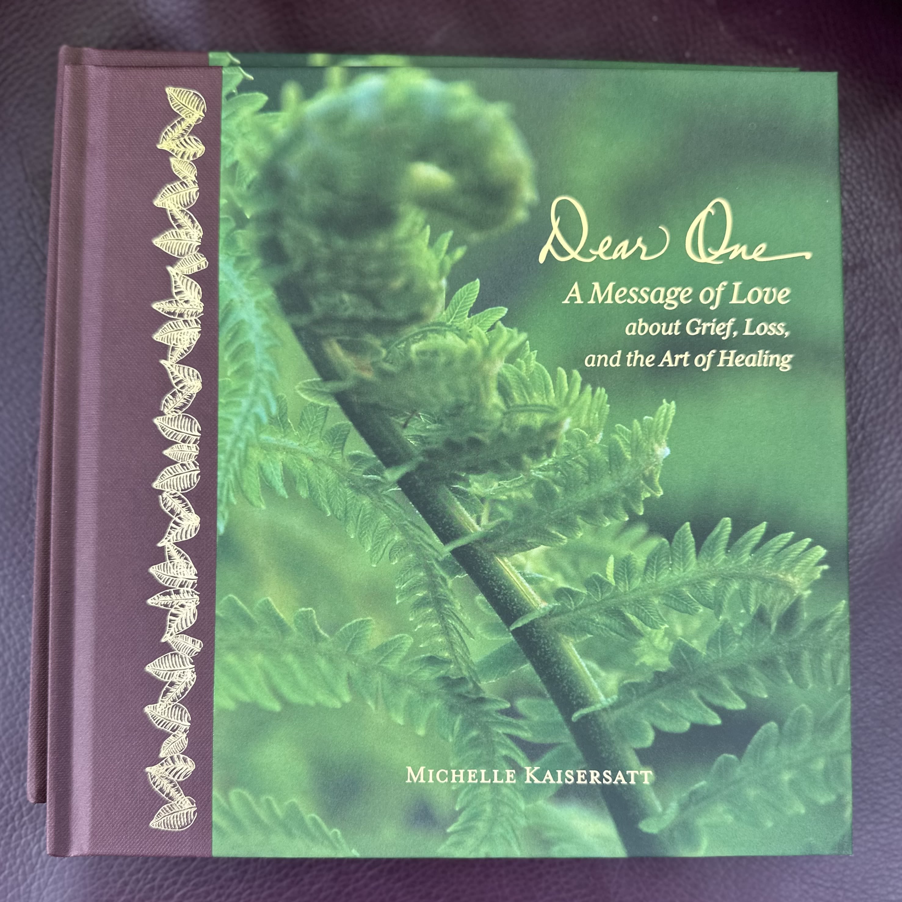 A purple hardcover book with a green plant cover and gold lettering.