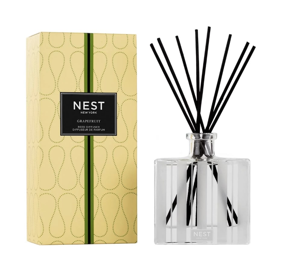 Reed diffuser with black sticks beside a yellow Nest New York box