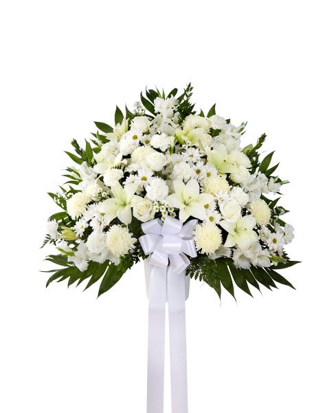 Large standing spray of white lilies, roses, and other flowers with a white bow and long ribbons