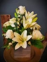 Cream lilies and roses arranged in a wooden basket