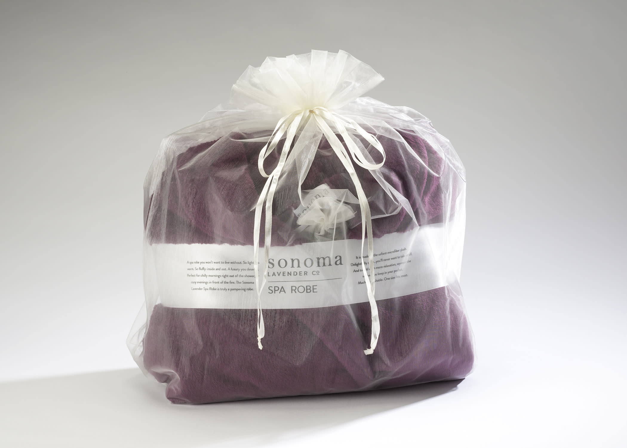 Purple spa robe packaged in a sheer white gift bag tied with ribbon