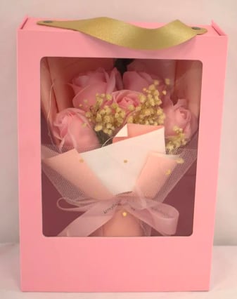 Pink boxed bouquet of pink roses and small yellow filler flowers wrapped in tulle with ribbon