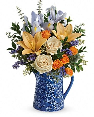Spring Beauty Bouquet - The etched botanical design and bold cobalt hue of this hand-glazed ceramic pitcher make it an extra special accompaniment for cheerful blue and gold blooms! CrÃ¨me roses, orange spray roses, peach asiatic lilies, light blue iris, and blue sinuata statice are accented with seeded eucalyptus, spiral eucalyptus, and myrtle. Delivered in a Spring Beauty Pitcher. 