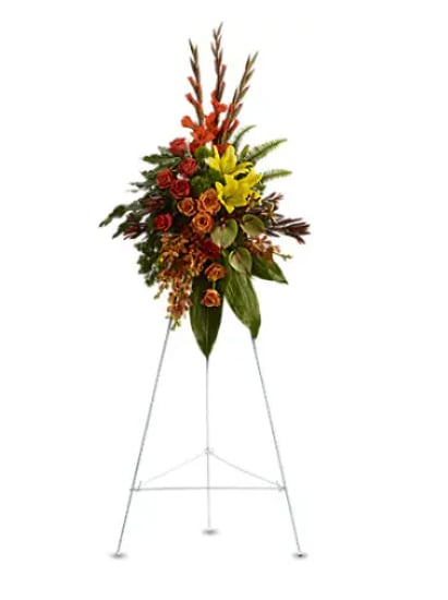 Standing floral spray with red, yellow, and orange flowers on a metal easel
