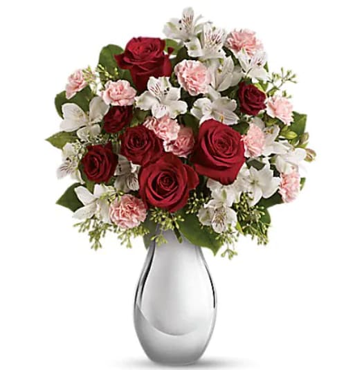 Red roses, pink carnations, and white alstroemeria in a glass vase