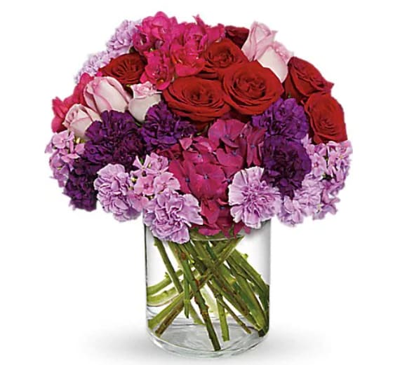 Bouquet of red, pink, and purple flowers in a clear glass vase