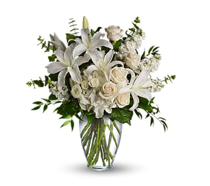 White lilies and roses arranged in a clear glass vase