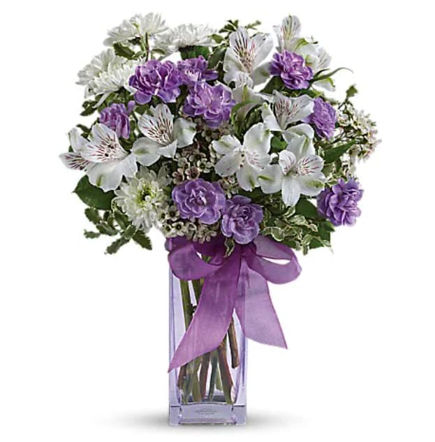 Purple and white bouquet in a clear glass vase with a ribbon