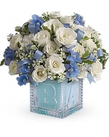 Baby's First Block - Blue - Celebrate the coolest baby boy on the block's arrival with this charming glass baby block that arrives chock full of pretty flowers. Perfect for baby showers, too! The glass block will make an adorable display piece for years! Dazzling white spray roses, light blue delphinium, white waxflower and light blue organza ribbon are delivered in a clear baby block with a light blue liner. One great delivery deserves another, don't you think? 