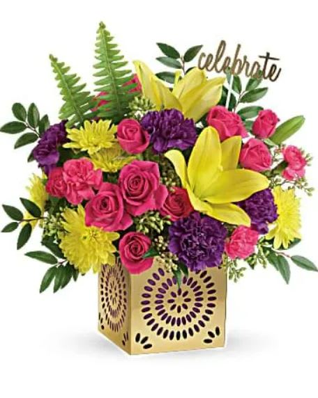 Colorful Celebration Bouquet - Color their day happy with this bright surprise! Artfully arranged with a Celebrate pick in a gleaming golden cube with delicate punched details, this sunny bouquet of yellow lilies and hot pink roses celebrates them in style. This joyful bouquet includes hot pink spray roses, yellow asiatic lilies, purple carnations, hot pink miniature carnations, yellow cushion spray chrysanthemums, huckleberry, seeded eucalyptus, and sword fern. Delivered in a Celebrate in Style cube. 