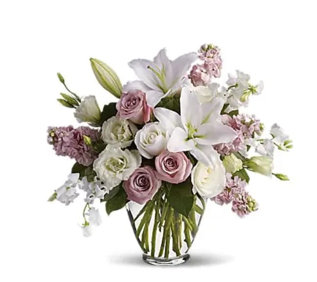 Bouquet of white lilies and pale pink roses in a clear glass vase