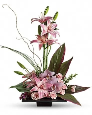 Imagination Blooms with Cymbidium Orchids - This towering topiary of asiatic lilies, orchids and roses - artistically arranged with tropical greenery - is a unique gift that celebrates the spirit of creativity. Pink asiatic lilies rise up from a square design block holding a mix of cymbidium orchids, spray roses and accent blooms and greenery. 