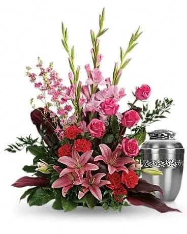 Pink lilies and roses arranged beside a silver urn