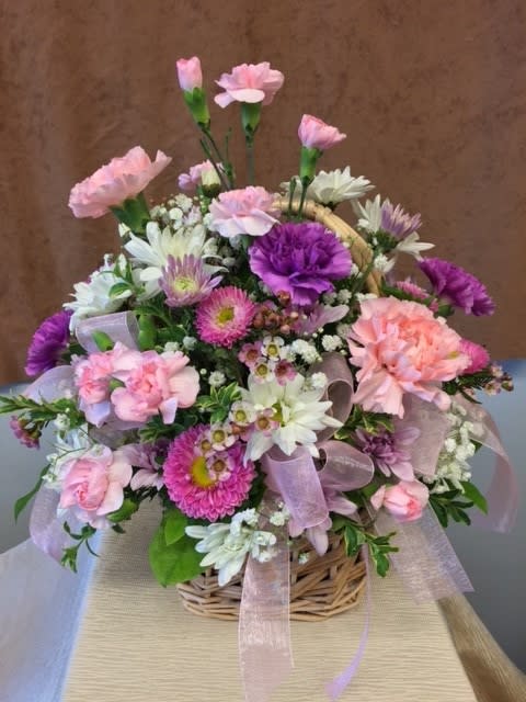 Basket arrangement of pink, purple, and white flowers with a ribbon