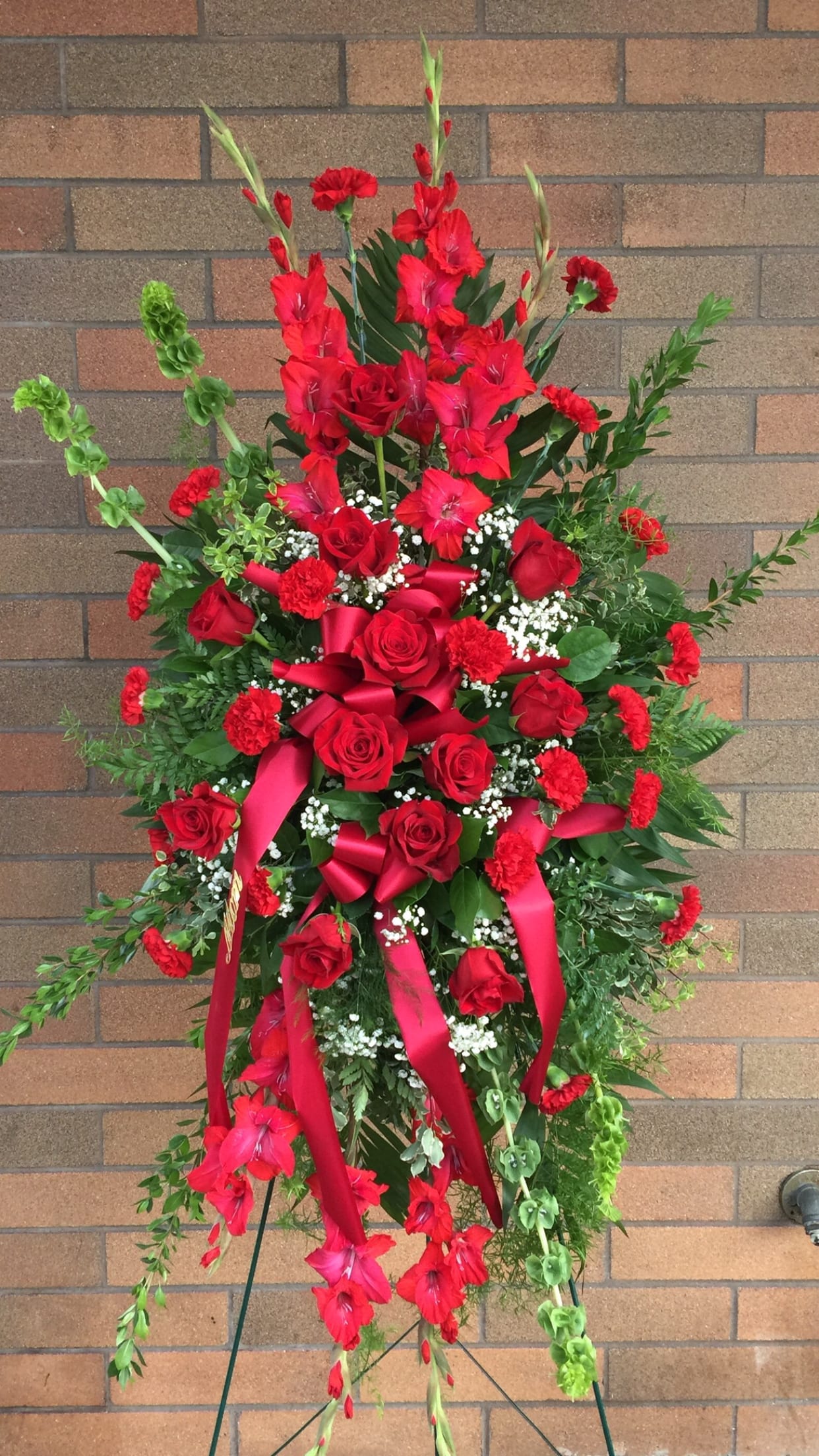 Tall red floral standing spray with roses and ribbons