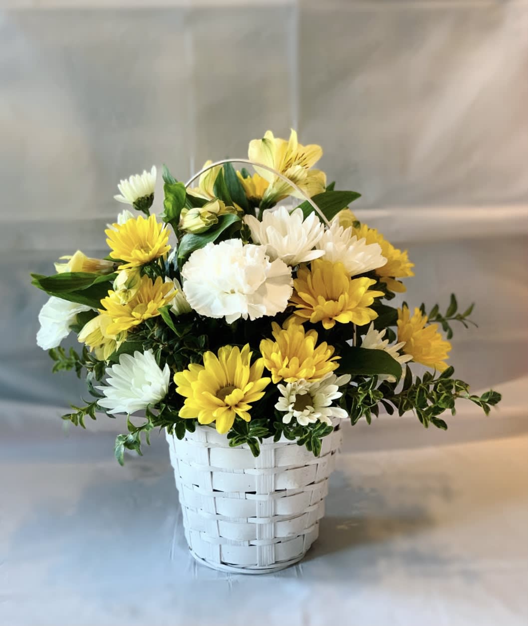 Yellow and white daisy bouquet in a white basket