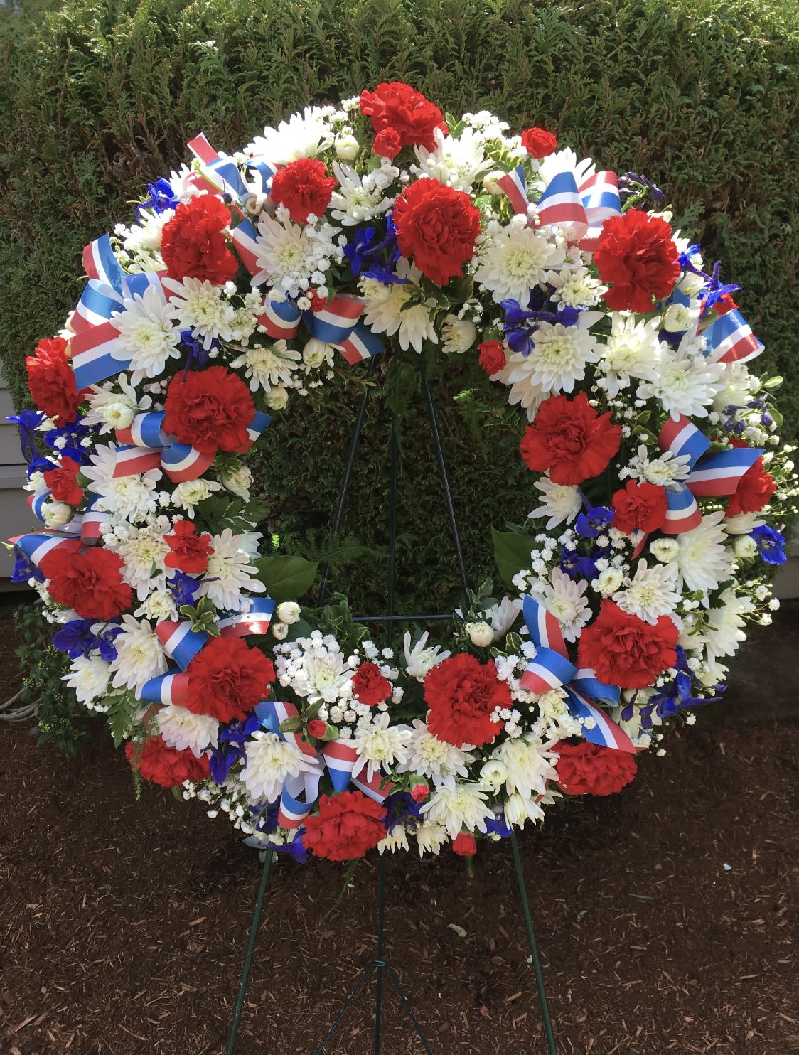 Large patriotic floral wreath with red, white, and blue flowers on a stand