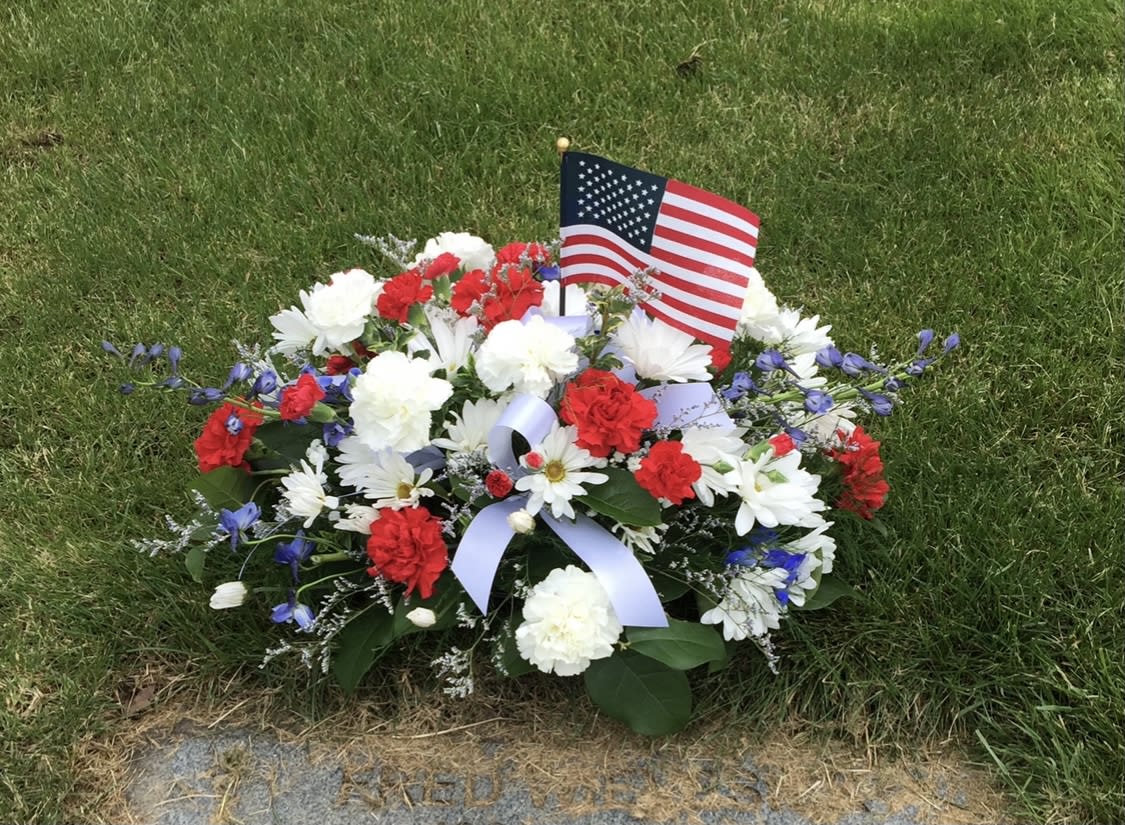 Red, white, and blue floral grave arrangement with an American flag