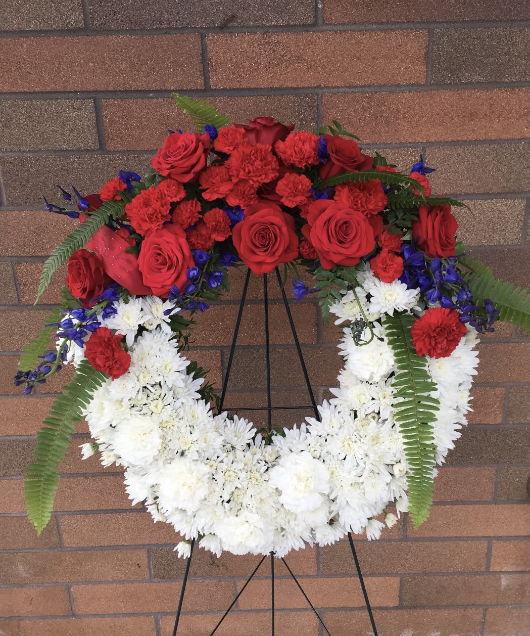 Red and white floral wreath on a black stand