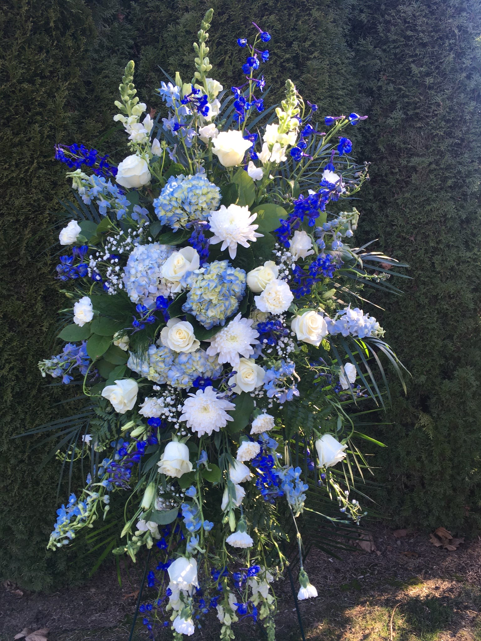 Tall blue and white floral standing spray with roses and hydrangeas