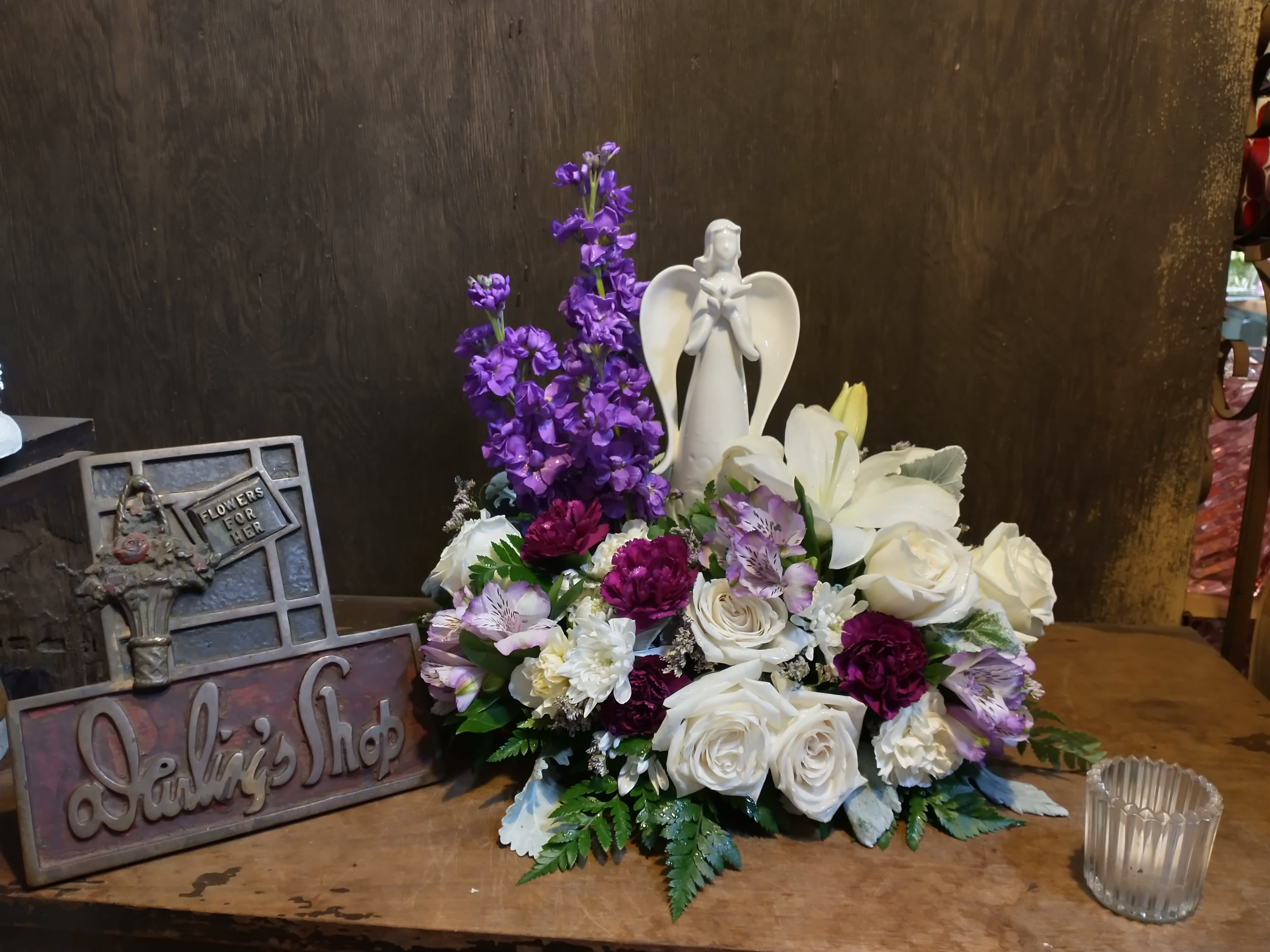 Purple and white floral arrangement with an angel figurine