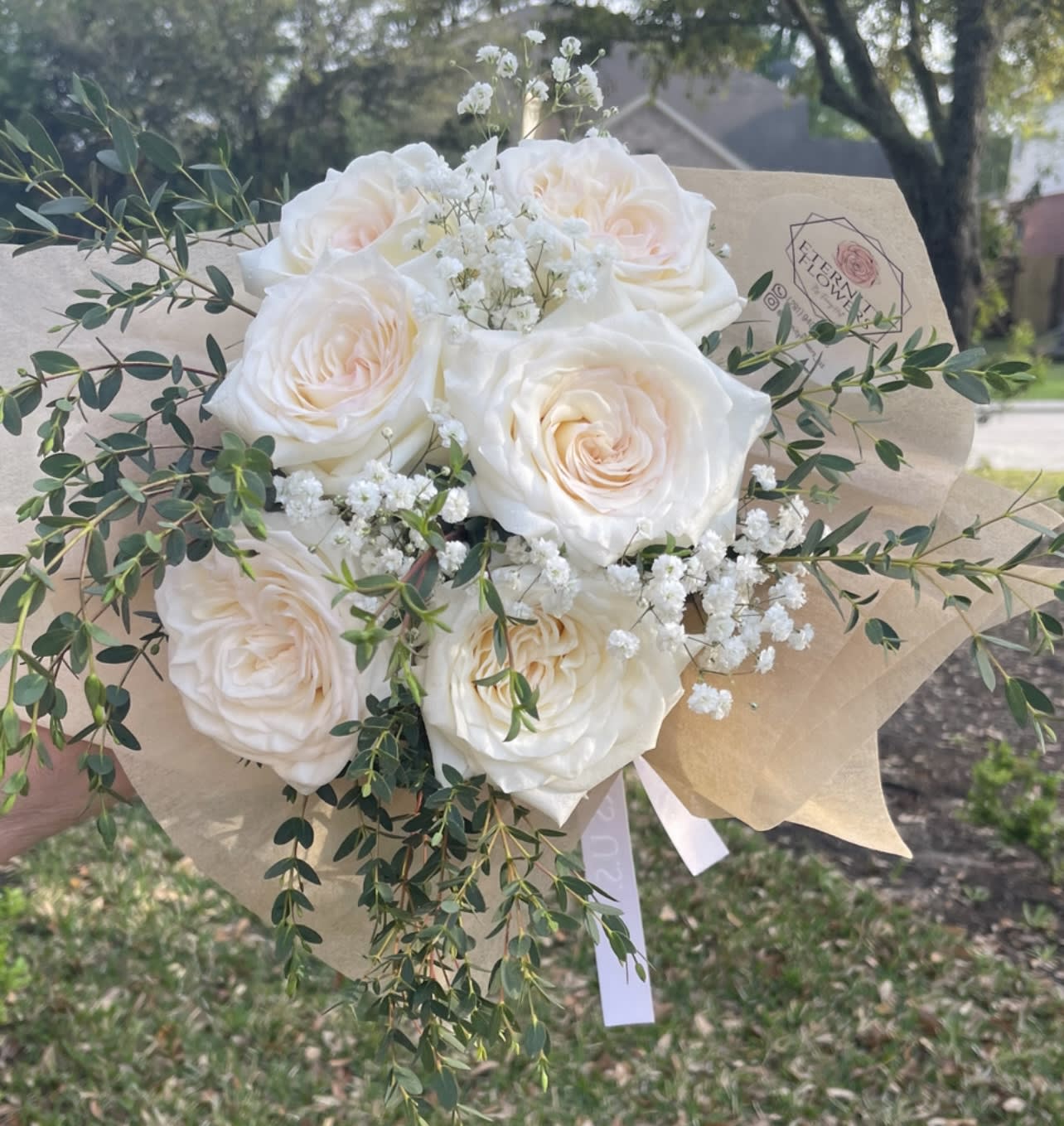 Bouquet of white roses with baby's breath and greenery in kraft paper