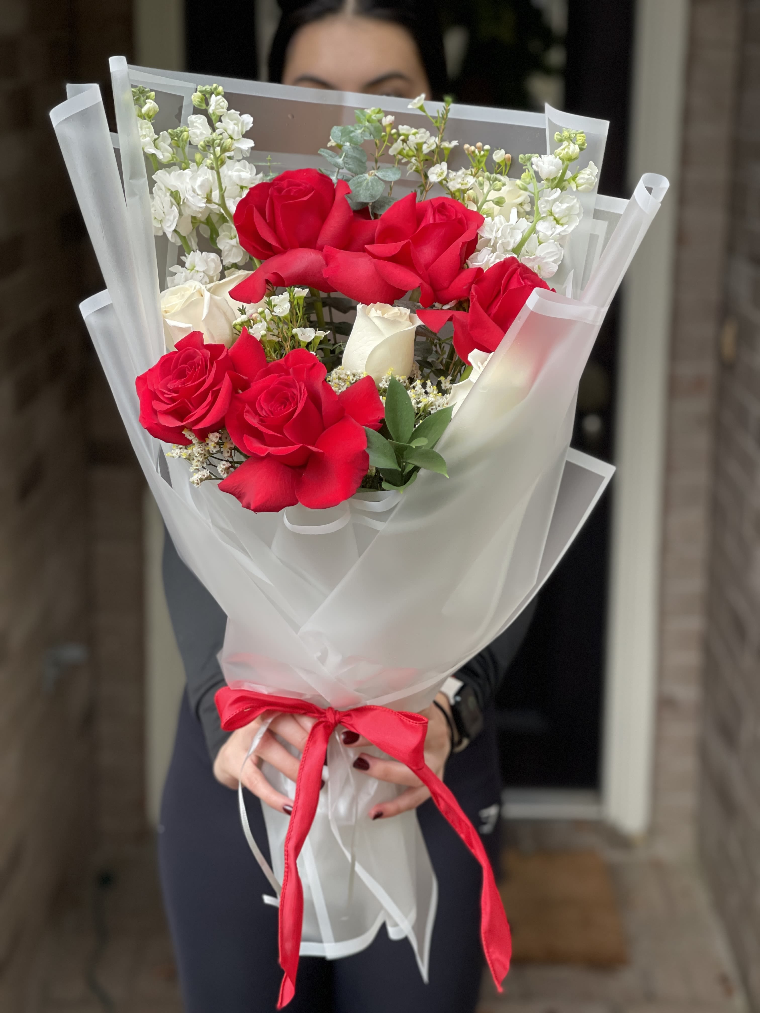Bouquet of red and white roses wrapped in white paper with a red ribbon