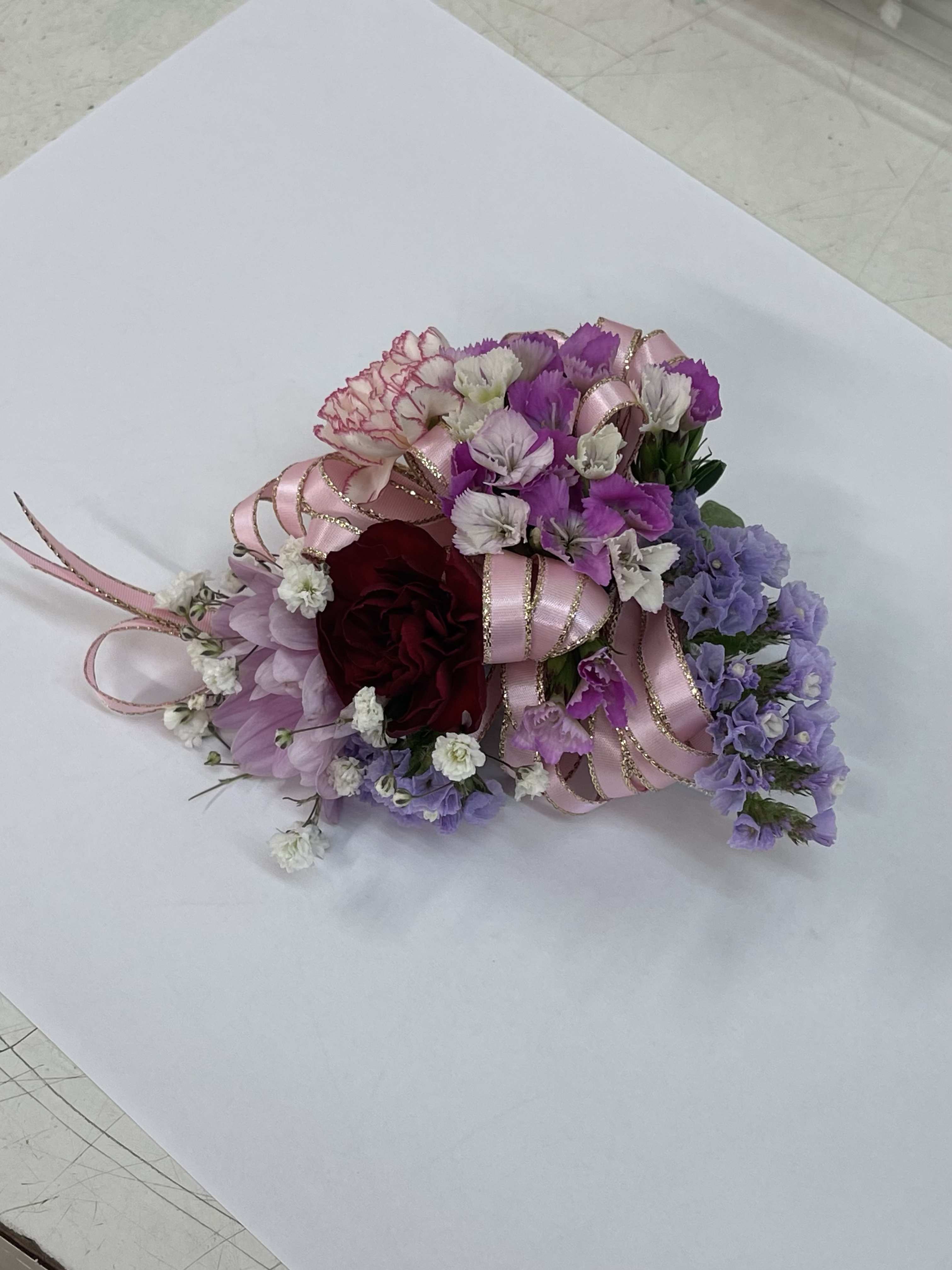 Small bouquet of pink, purple, and white flowers with ribbon accents