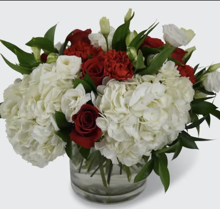 White hydrangeas and red roses arranged in a clear glass vase
