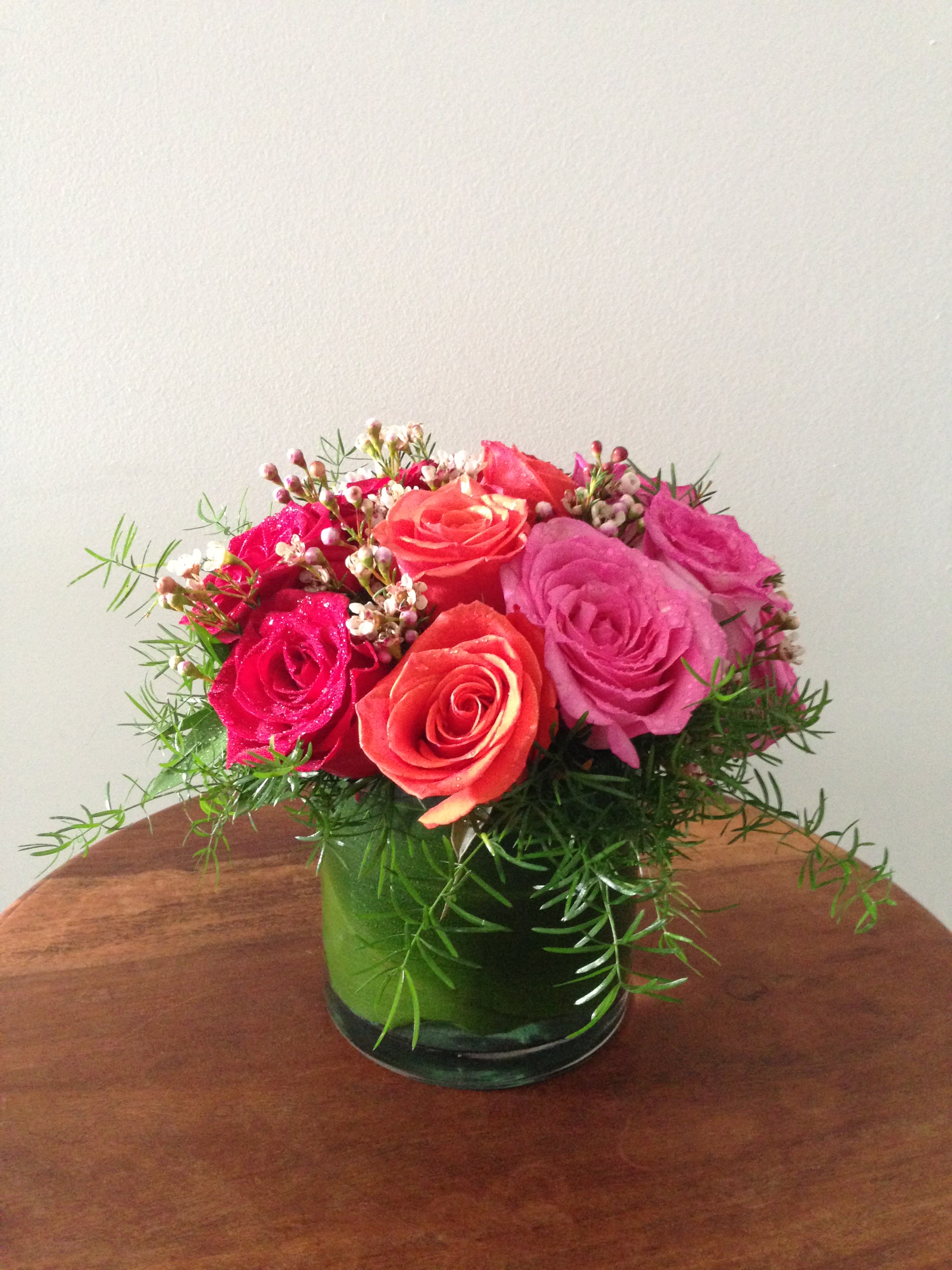 Pink and coral roses arranged in a green glass vase