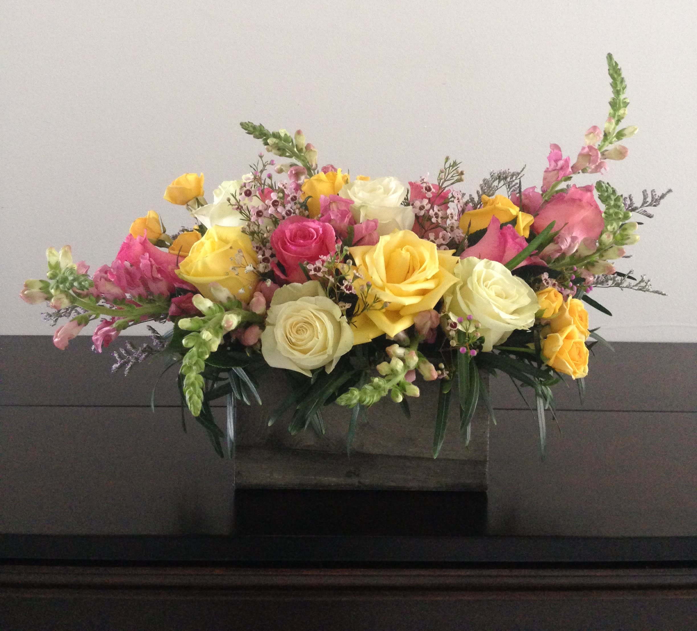 Mixed bouquet of yellow, pink, and white roses in a low container