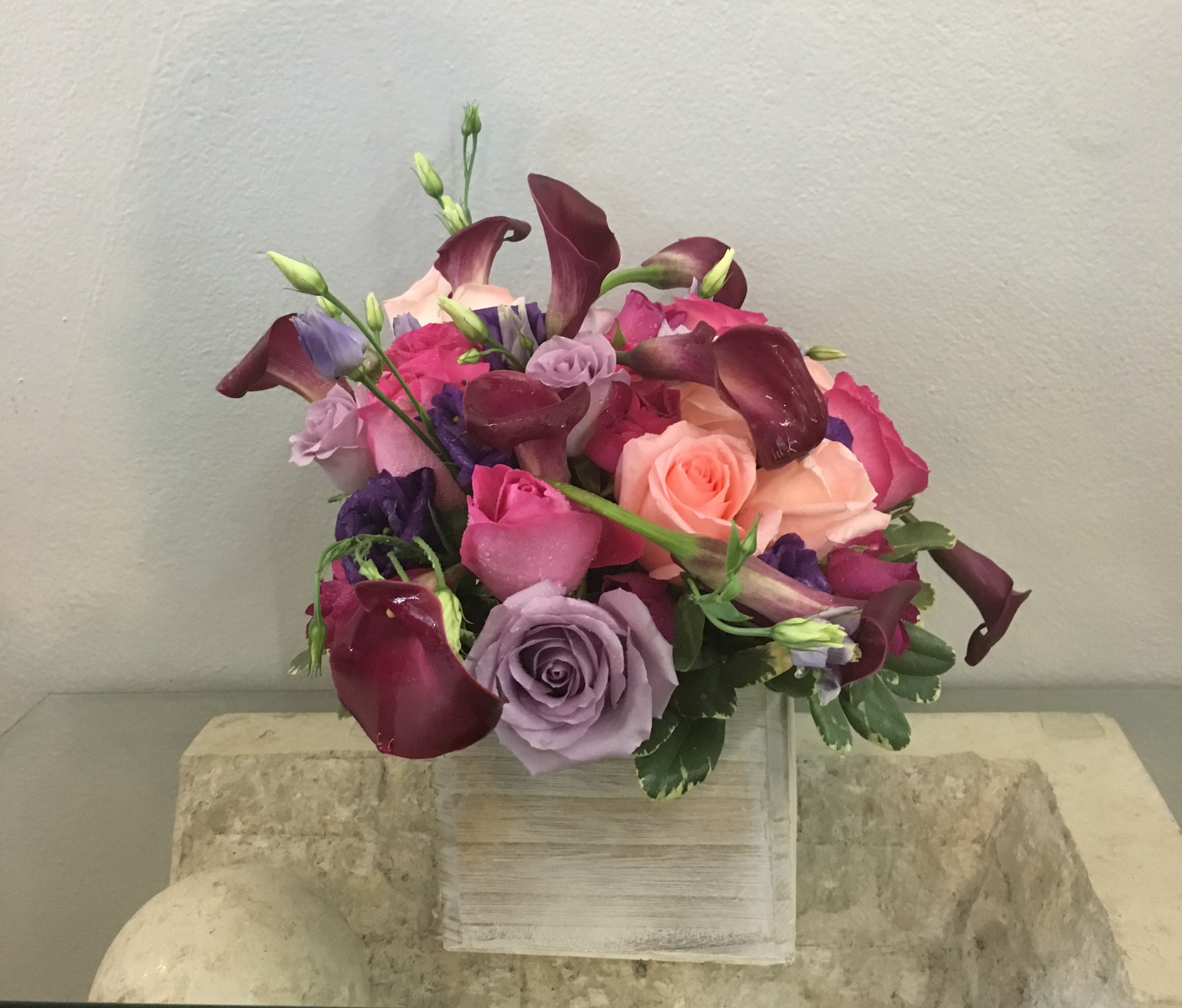 Bouquet of roses and calla lilies in pink, purple, and burgundy tones