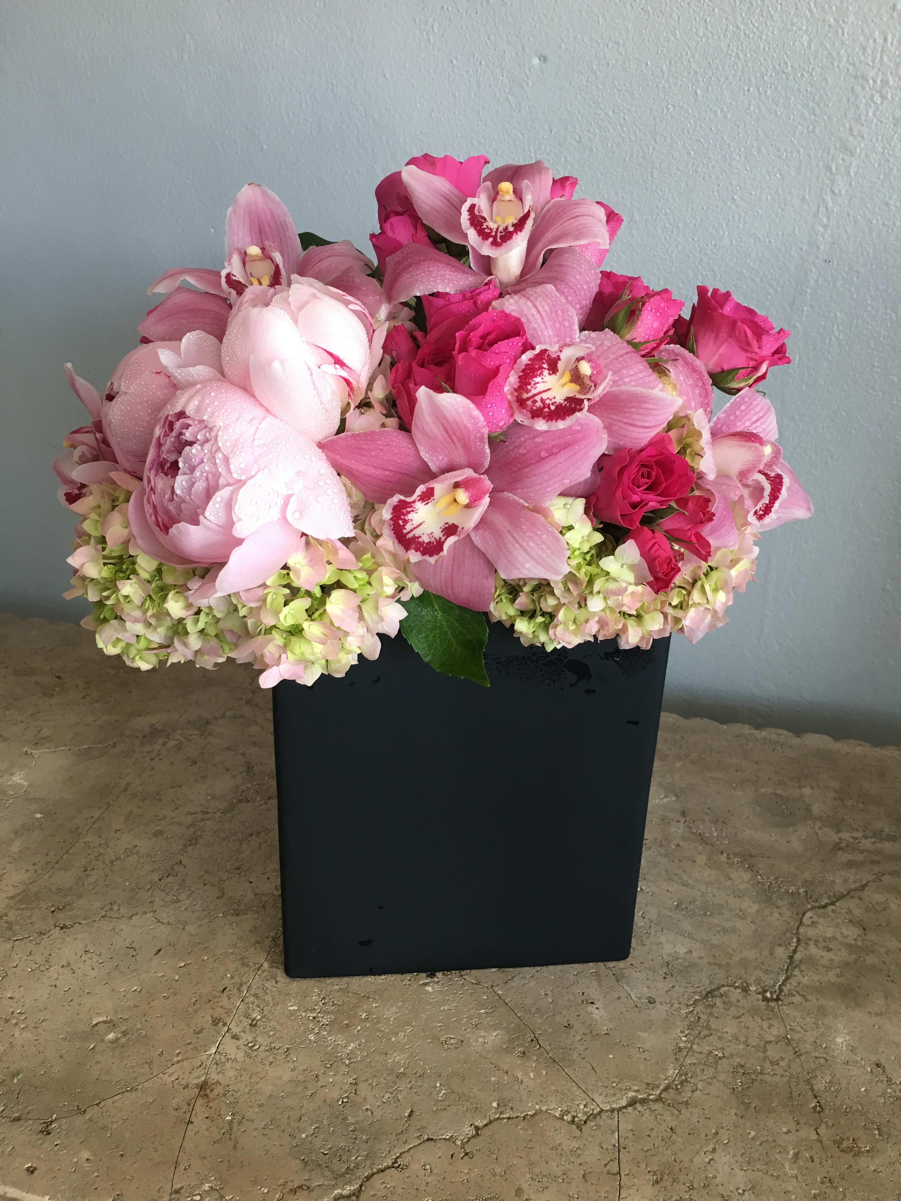 Pink orchid and rose arrangement in a black rectangular vase