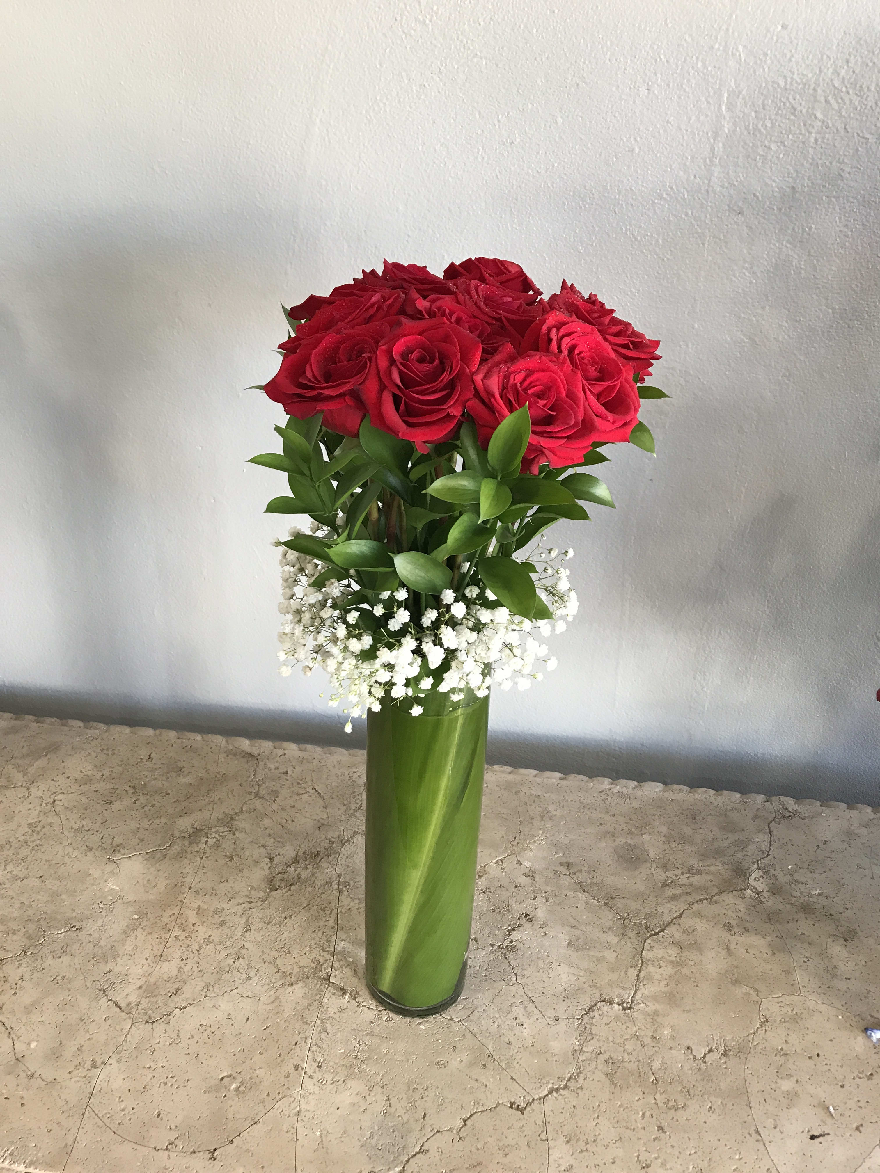 Red roses in a tall green vase with white baby's breath
