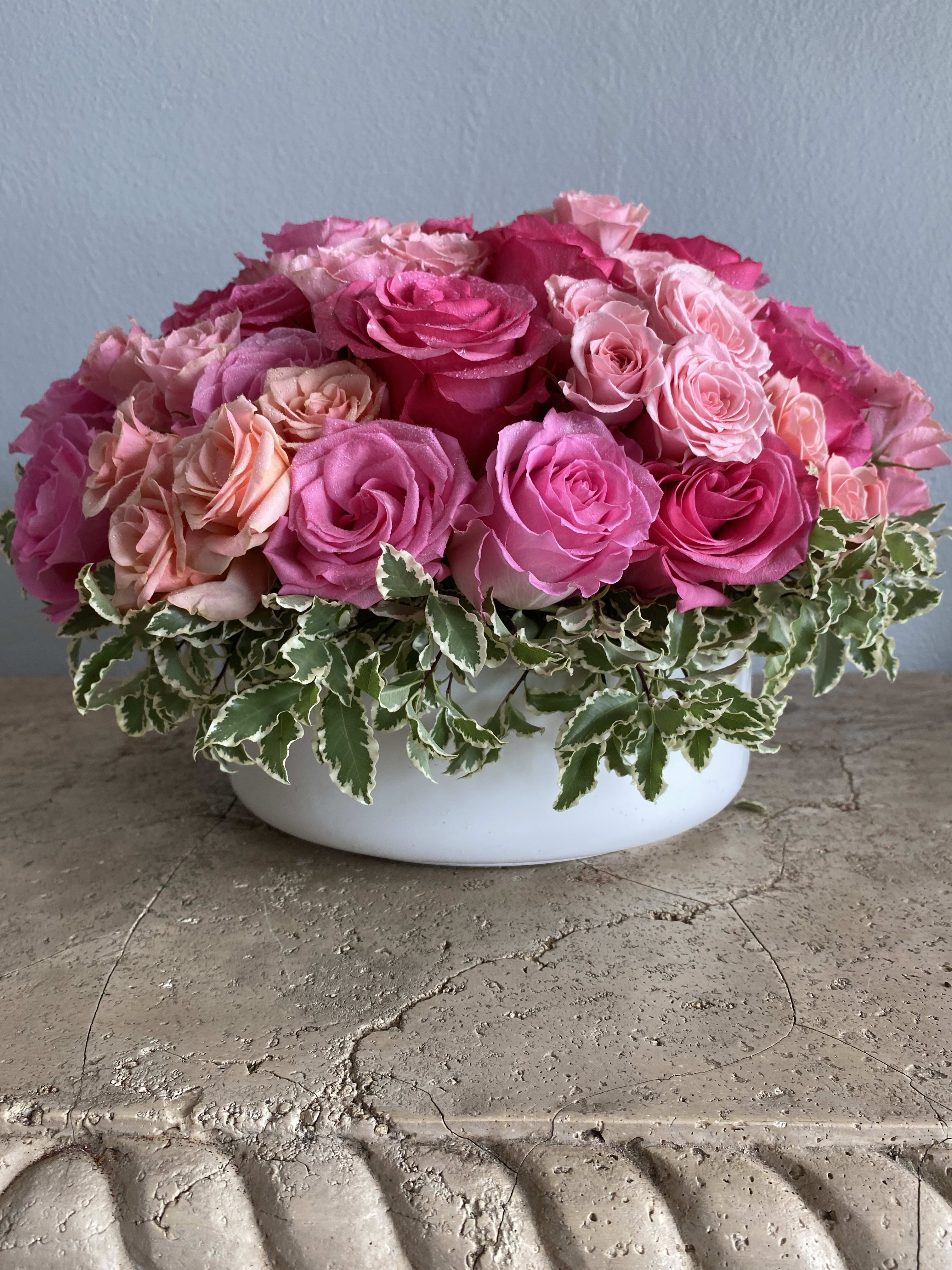 Pink and peach roses arranged in a white bowl vase