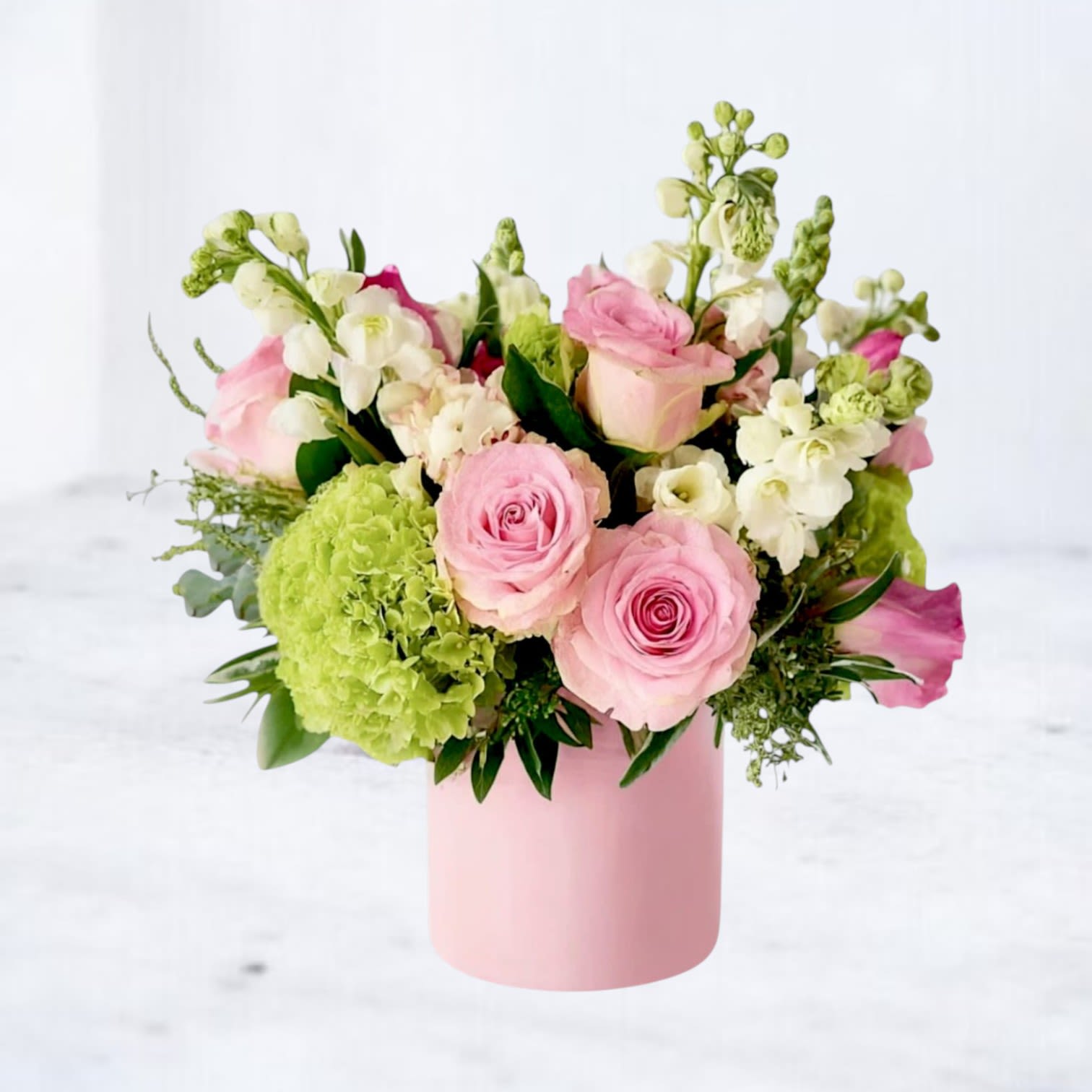 Pink Lemonade - Bring a splash of joy to any occasion with Pink Lemonade — a cheerful and refreshing arrangement that blends the sweetness of blush roses, creamy stock, and lime-green hydrangeas with playful accents of peach snapdragons and hypericum berries. Hand-designed in a soft pink vase, it’s a modern floral delight bursting with energy and springtime magic.  Whether you're celebrating a birthday, welcoming a new baby, or simply making someone’s day a little brighter, this bouquet delivers happiness in every petal.