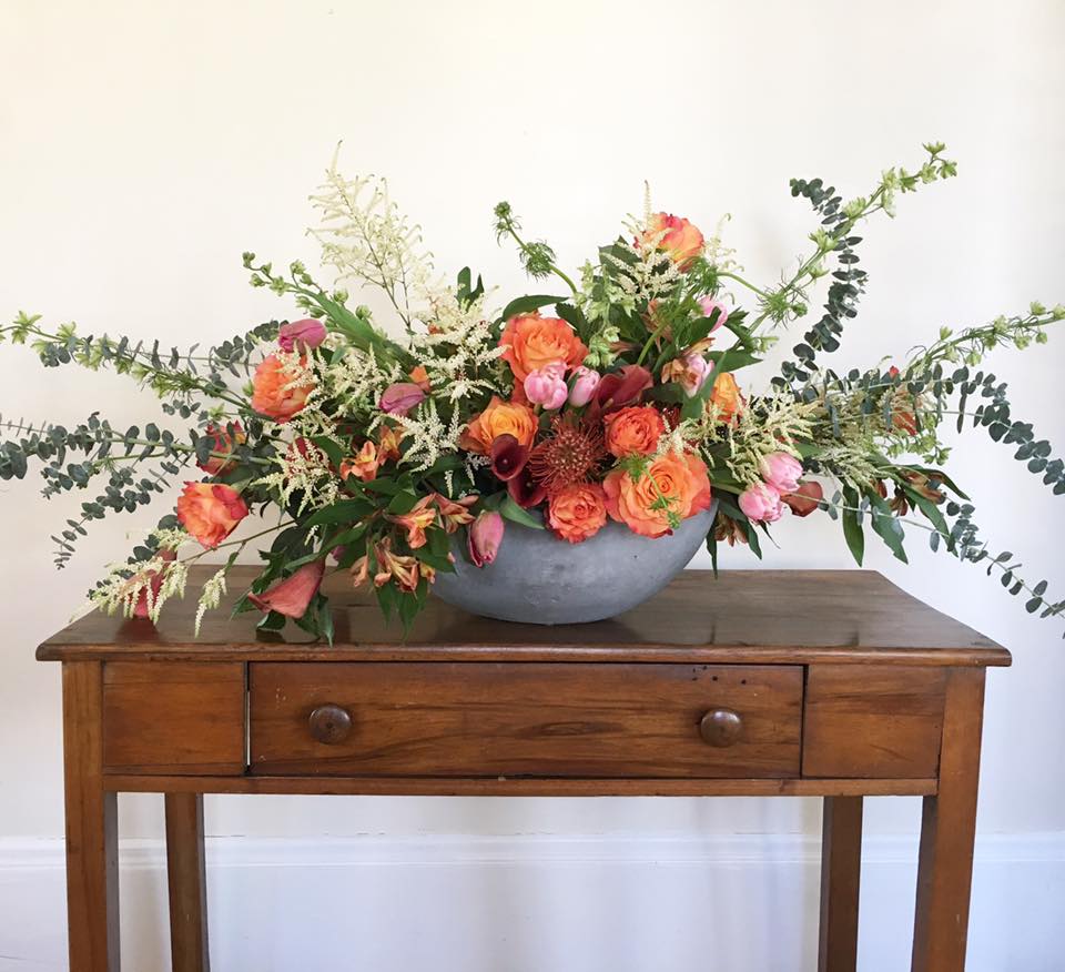 Low floral arrangement in a gray bowl with orange and pink blooms