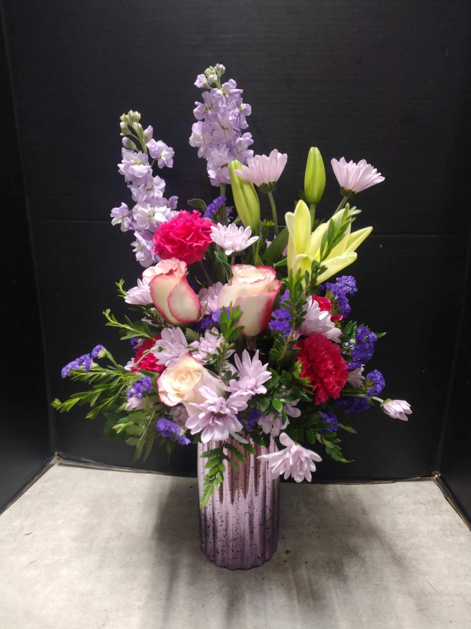 Mixed bouquet in a purple vase with pink, lavender, and yellow flowers