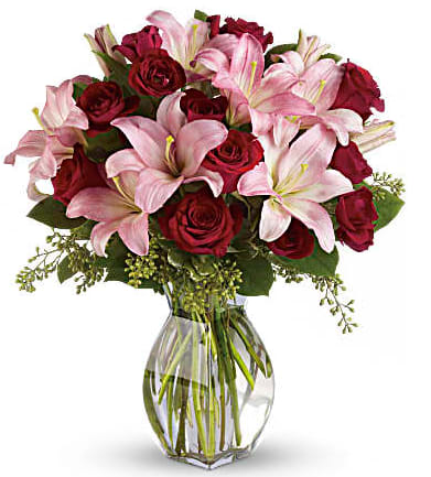 Bouquet of pink lilies and red roses in a clear glass vase