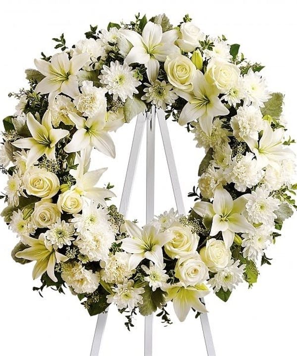 White floral wreath on a standing easel with ribbon