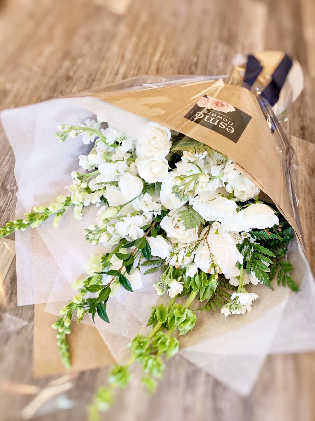 White flower bouquet wrapped in brown paper and clear plastic