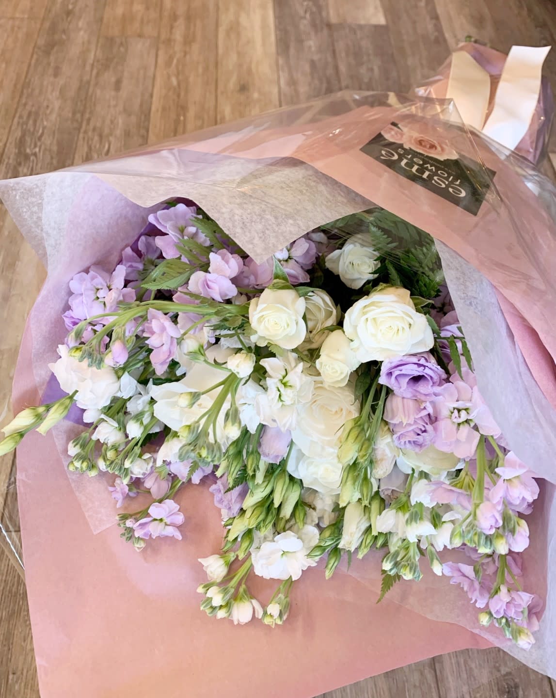 Bouquet of white roses and lavender flowers wrapped in pink paper