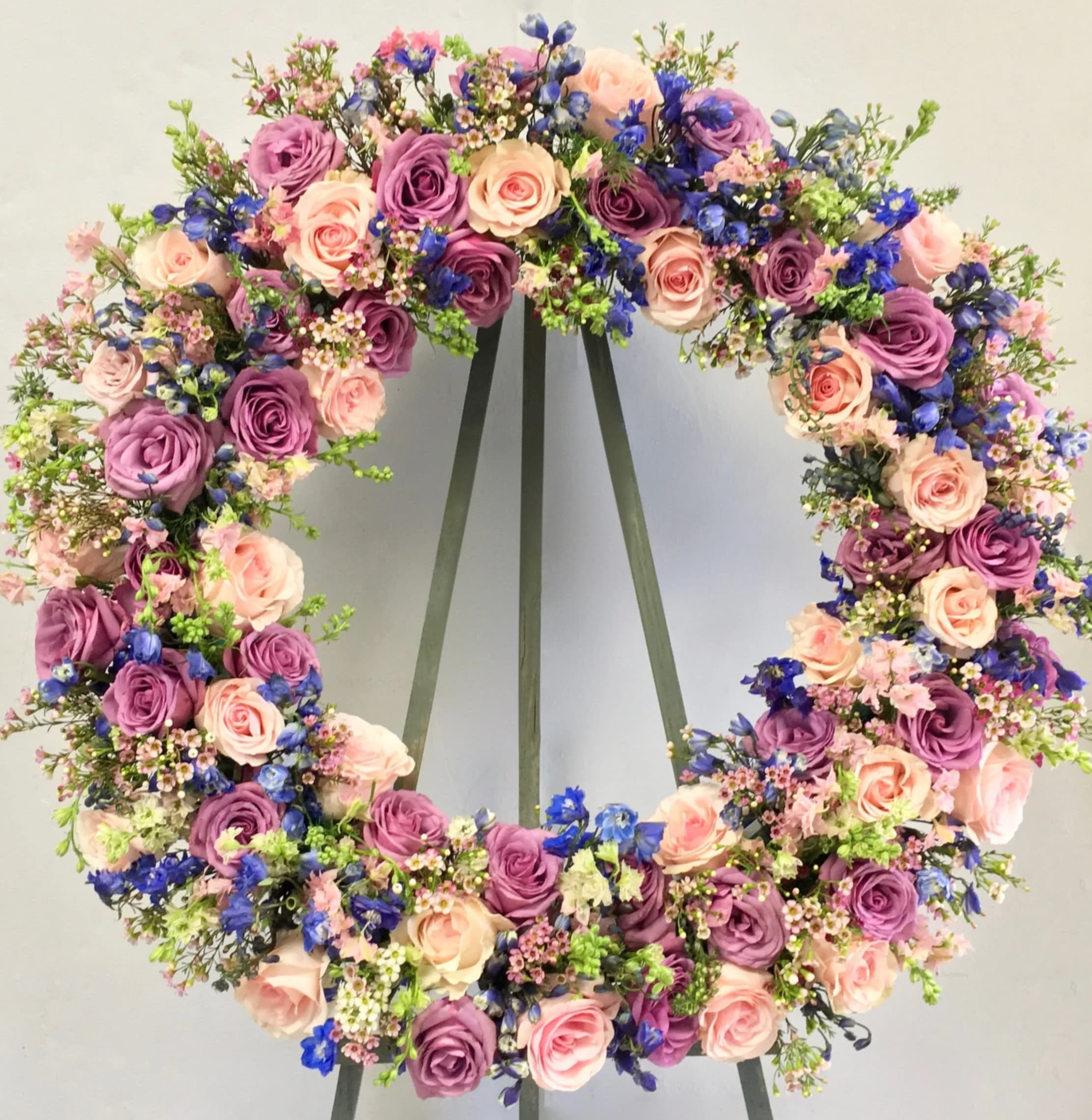Circular floral wreath with pink, purple, and blue flowers on a stand
