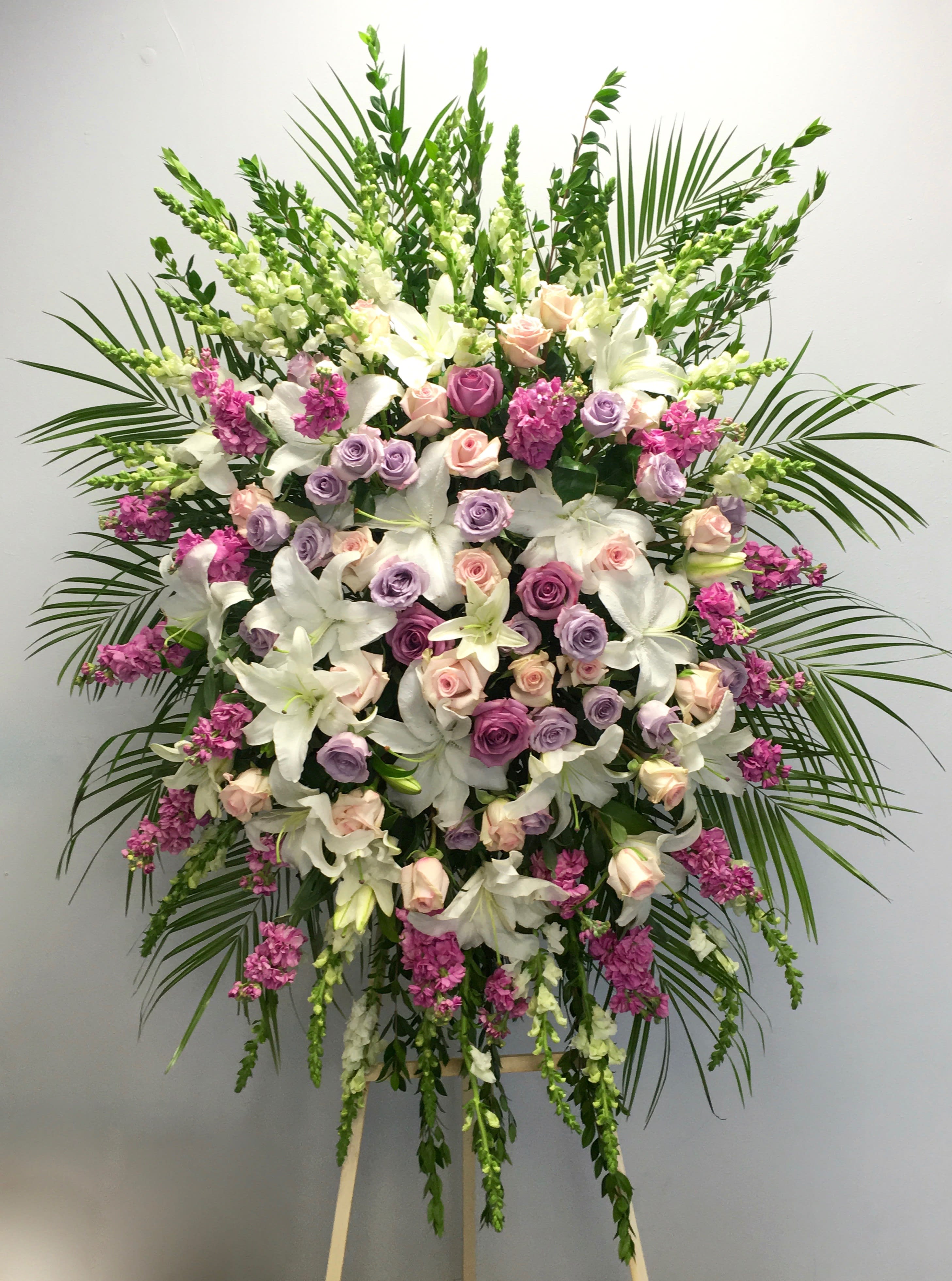 Standing floral spray with white lilies, pink and lavender roses, and magenta accents